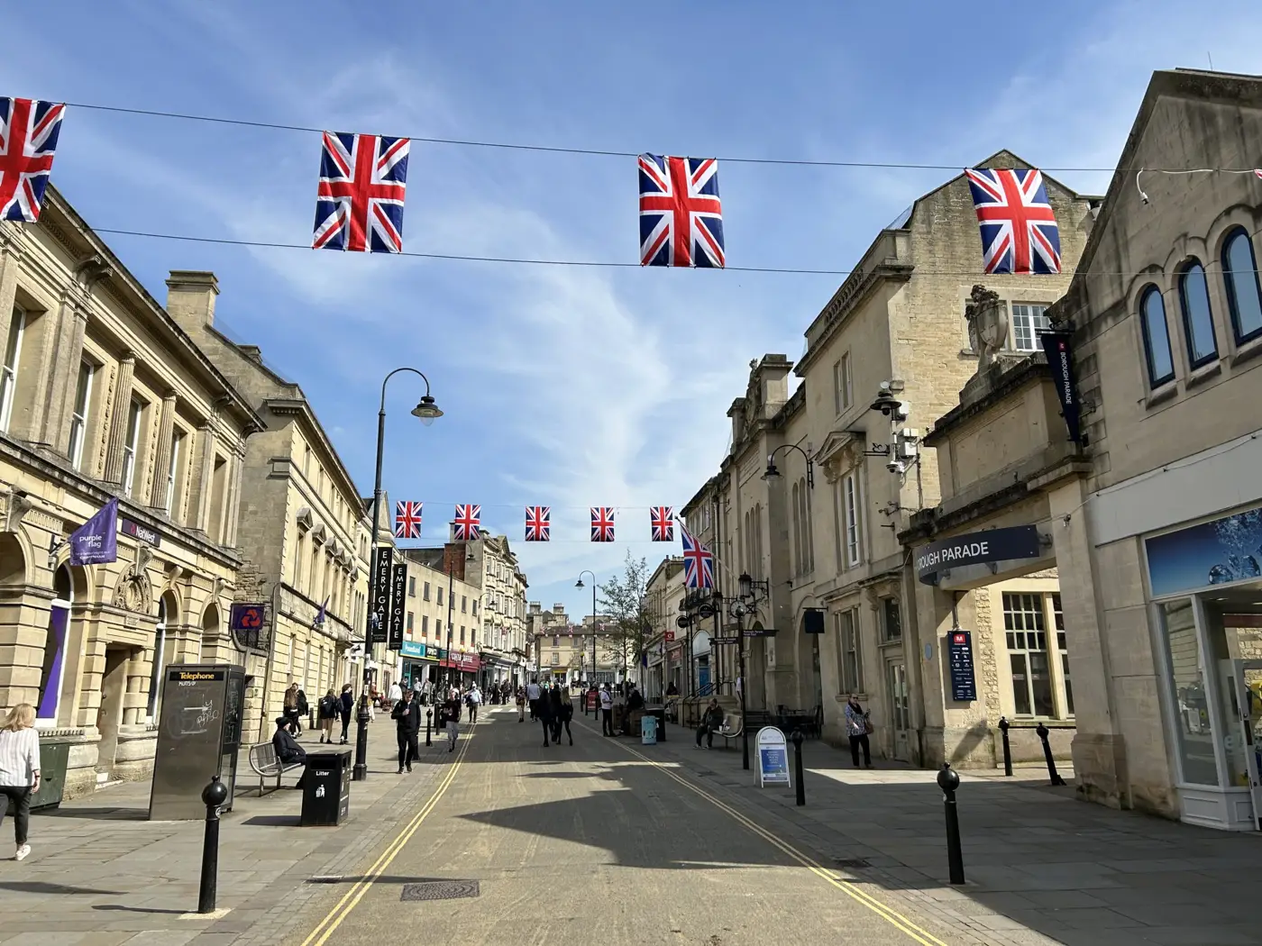 Chippenham High Street on a sunny day, with Union Jack bunting strung between the stone buildings